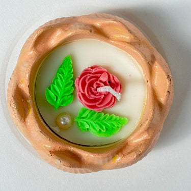 Decorative soap with a pink rose, green leaves, and pearl on a white background